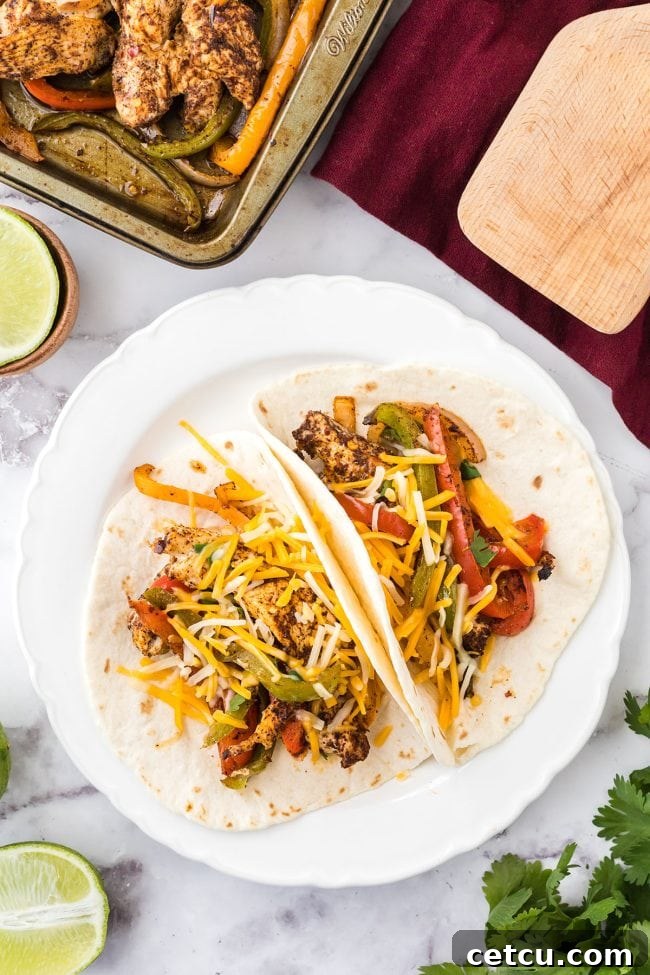 Two servings of sheet pan chicken fajitas on plates with tortillas and lime wedges.