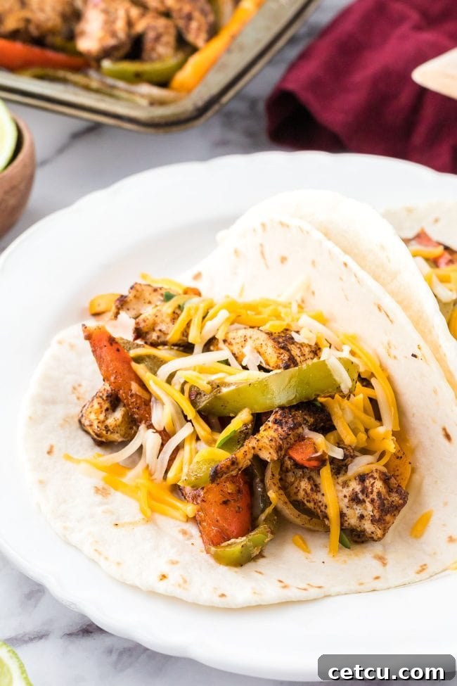 Homemade oven fajita wrapped in a flour tortilla, showcasing the chicken and vegetable filling.