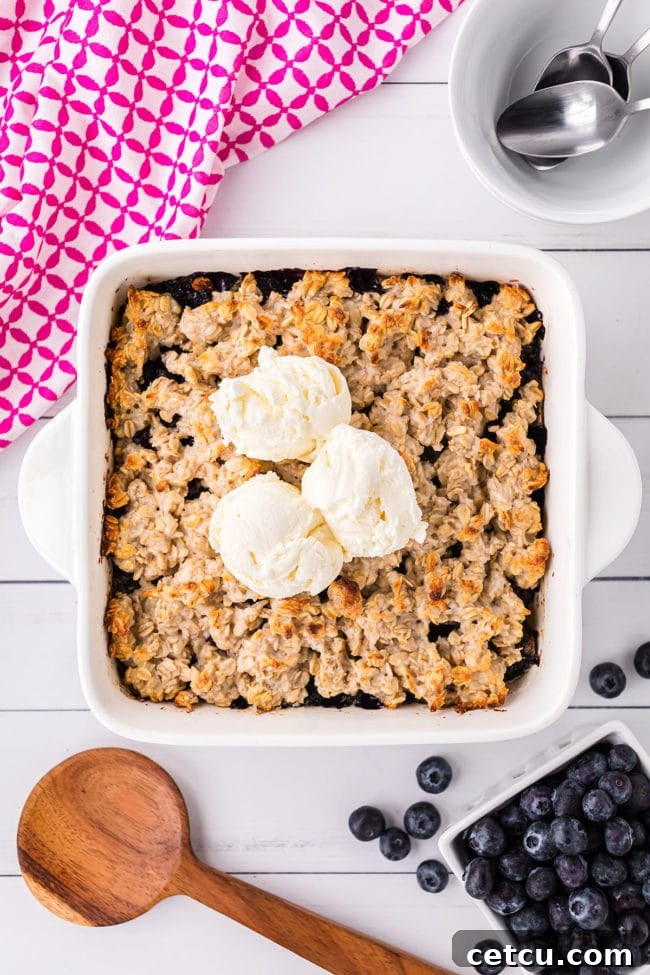 baking dish with warm blueberry crisp topped with 3 scoops of vanilla ice cream