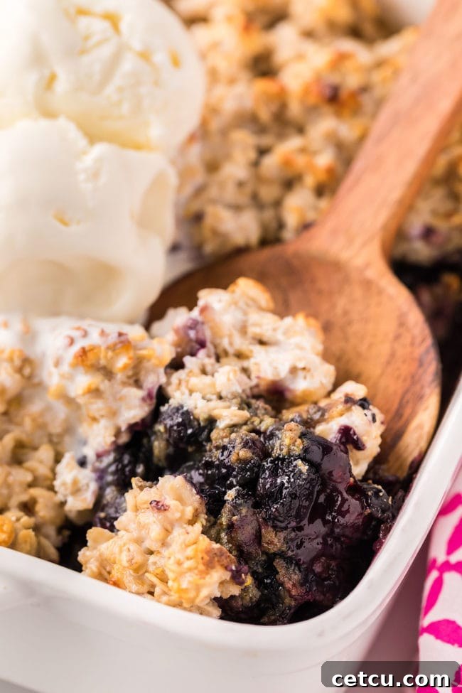 baking dish with fruit crisp and wooden serving spoon