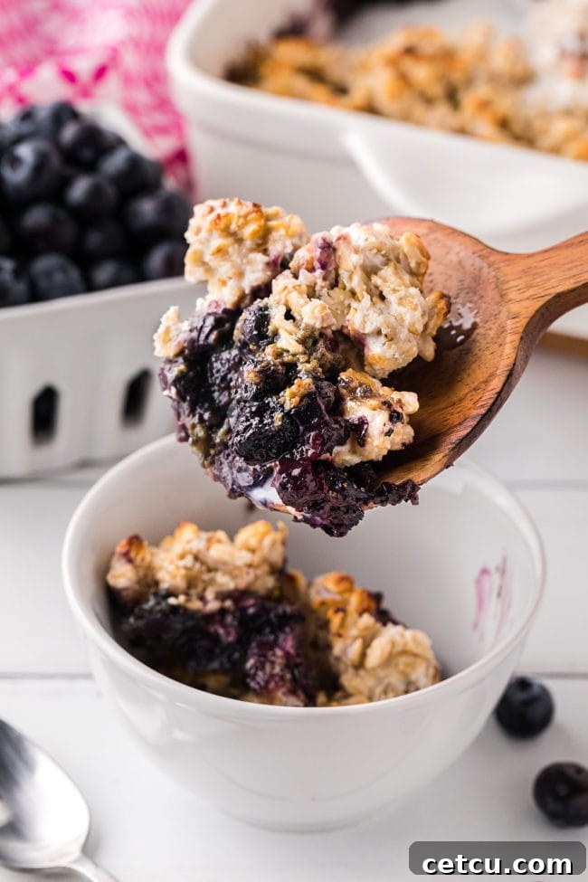 berry crisp on a large wooden spoon