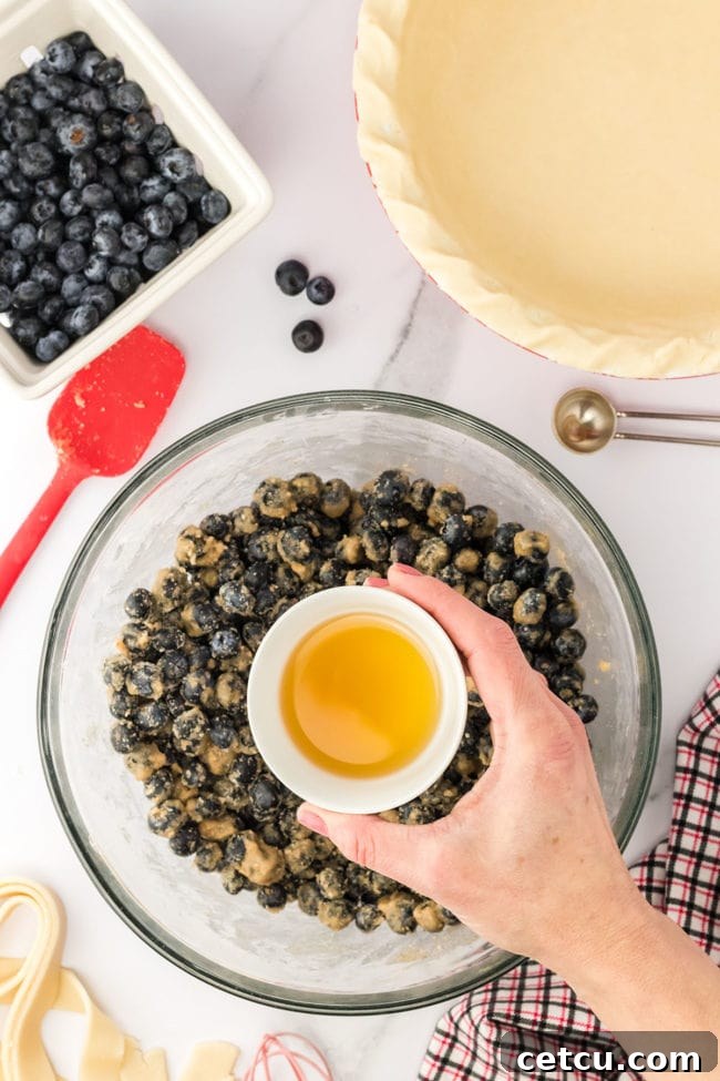 Step two: adding blueberries and bourbon to the dry ingredients in a glass mixing bowl and stirring to coat.