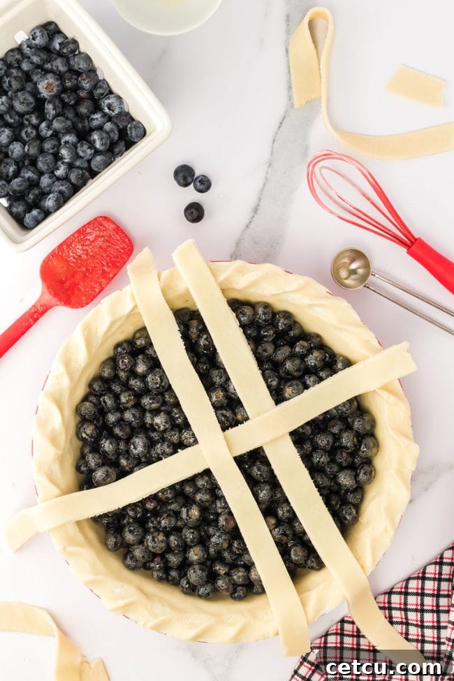 Step three: expertly weaving pastry strips to form a lattice crust over the blueberry filling in a pie dish.