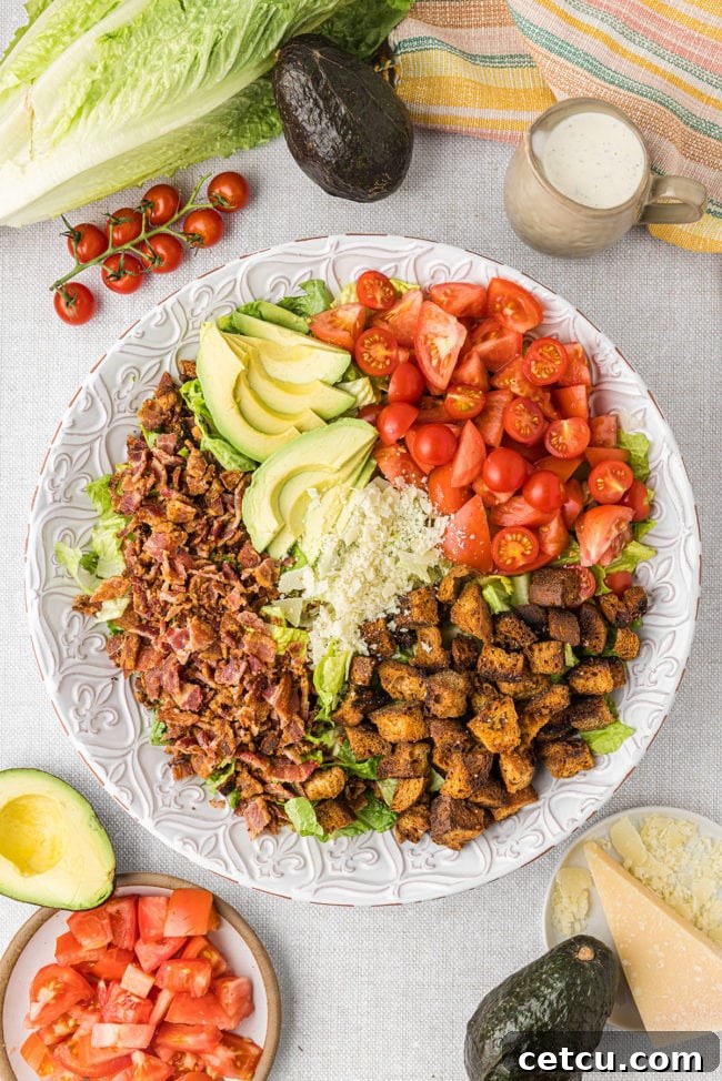 A BLT salad beautifully assembled on a plate, garnished with fresh avocado slices, showcasing the final presentation.