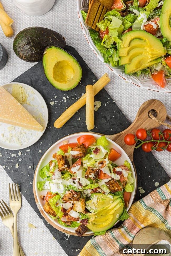 An overhead flat lay shot of a white bowl filled with BLT salad, garnished with fresh avocado and shredded Parmesan cheese, showcasing its enticing presentation.