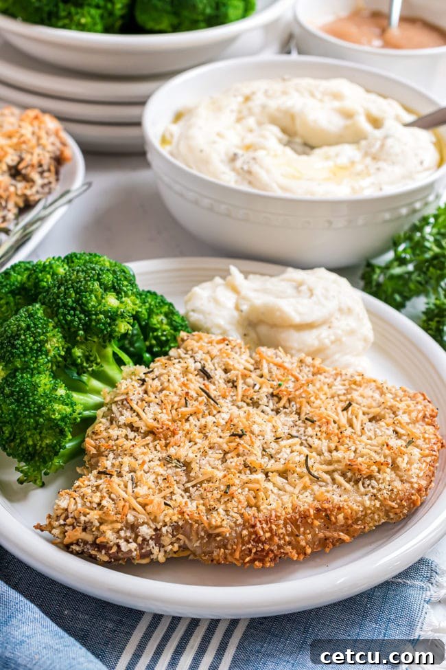 Oven-Baked Crusted Parmesan Pork Chops served with steamed broccoli and creamy mashed potatoes, showcasing a golden-brown crust.
