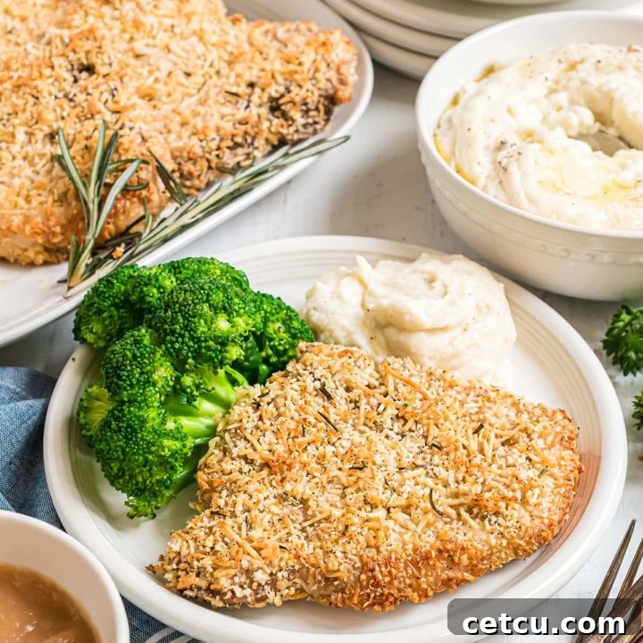 parmesan crusted baked pork chops on a plate with broccoli and mashed potatoes