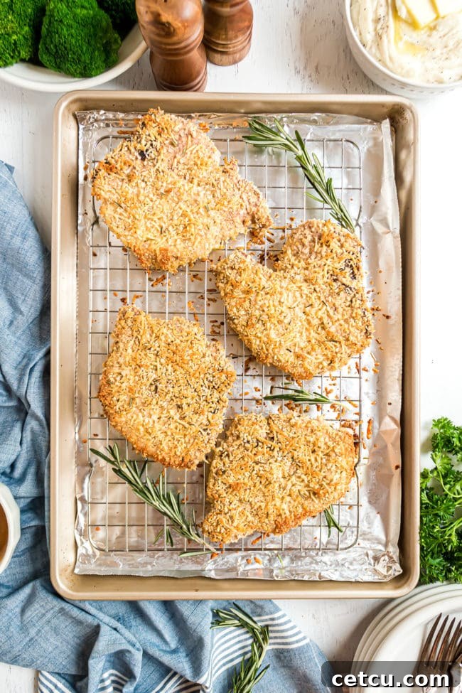 Freshly baked Oven-Baked Parmesan Pork Chops with a golden-brown, crispy crust, resting on a wire rack after cooking.