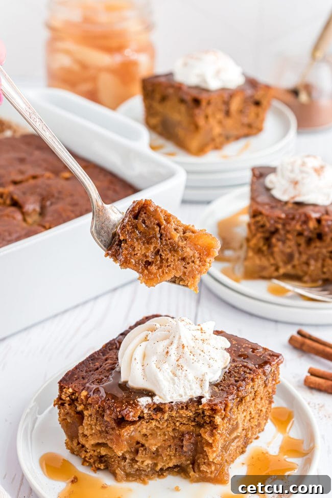 Spiced Apple Gingerbread Cake 11 A fork holding a perfect bite of gingerbread apple cake, showcasing its moist texture and the rich topping, tempting anyone nearby.