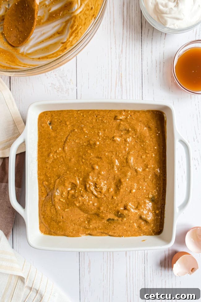 Spiced Apple Gingerbread Cake 6 A pristine white square baking dish, lightly greased and ready, holds the rich, spiced gingerbread apple cake batter, smoothed evenly across the bottom.
