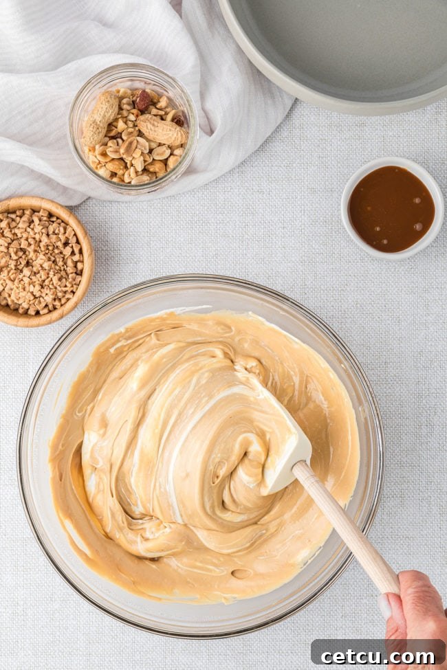 A rubber spatula meticulously mixing a dessert dip in a glass bowl, ensuring all ingredients are perfectly combined for a smooth consistency.
