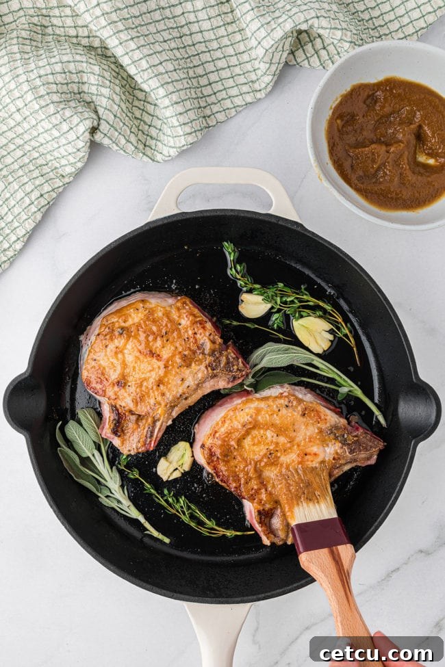 glazed pork chops in a cast iron skillet with fresh herbs