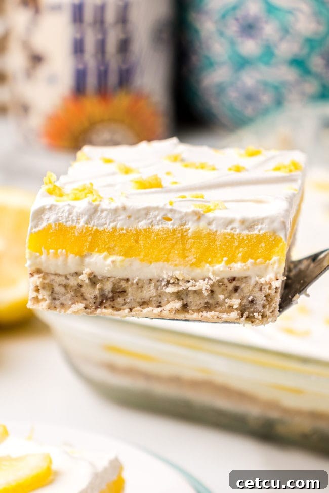 A serving of creamy Lemon Lush dessert being lifted from the pan with a spatula, displaying its perfectly set layers and inviting texture. This final step image highlights the readiness of the dessert to be enjoyed.