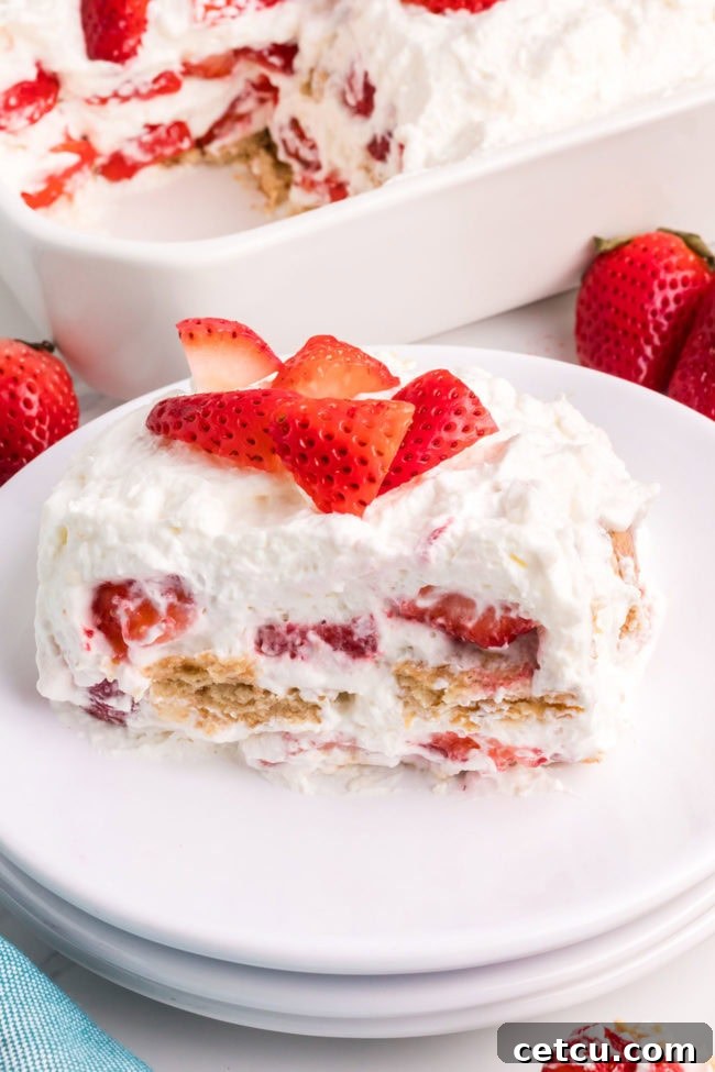 A vibrant fresh strawberry icebox cake topped with whole and sliced strawberries, highlighting its irresistible freshness.