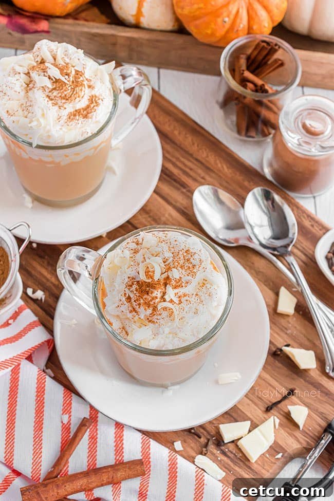 Two inviting mugs of pumpkin spice hot chocolate, garnished with whipped cream and a light sprinkle of cinnamon, set against a cozy backdrop.