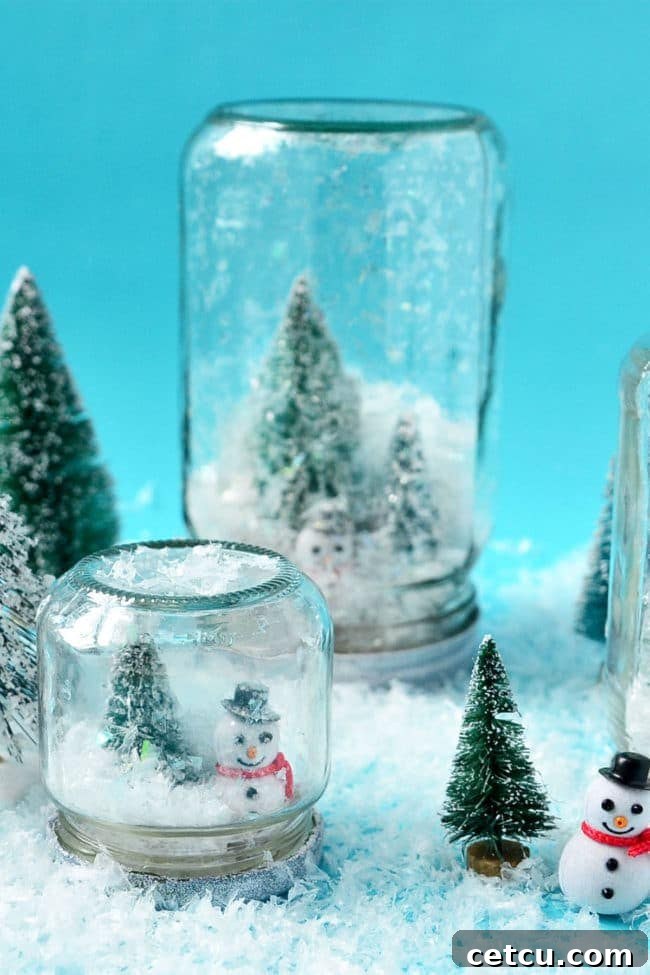 Several finished waterless snow globes featuring miniature trees and snowmen inside jars.