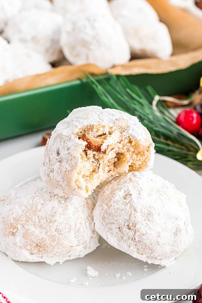 A close-up view of delicate snowball cookies (Russian Tea Cakes) artfully arranged in a vibrant green dish.