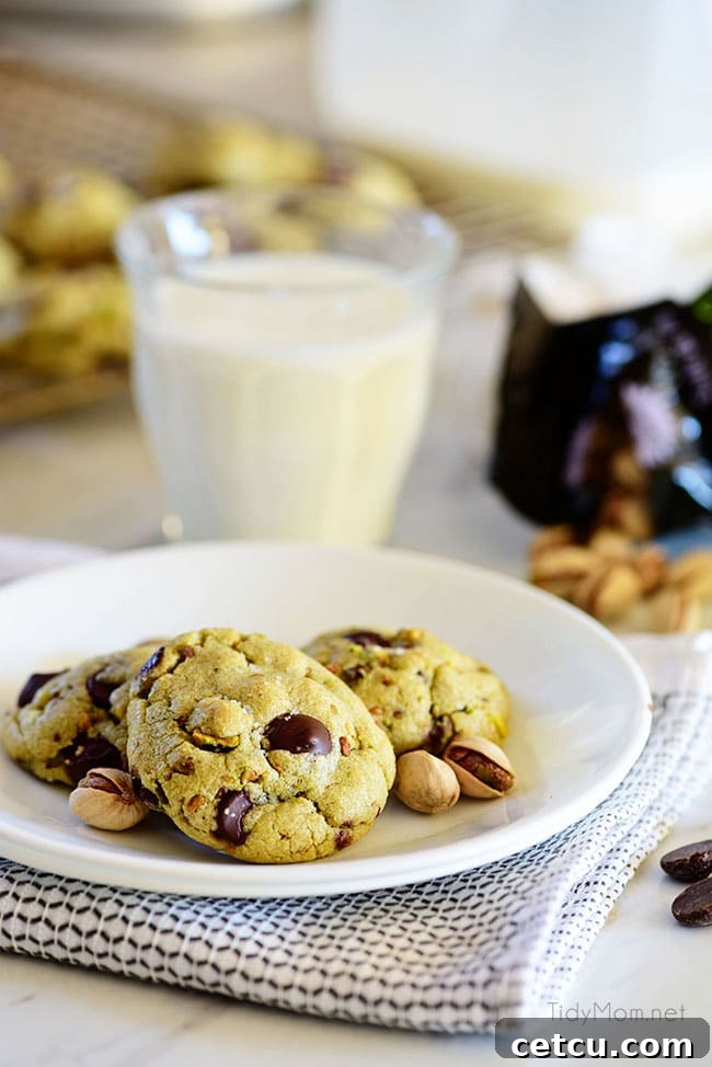 Delicious Pistachio Cookies with Dark Chocolate chunks, served on a plate with a glass of milk.
