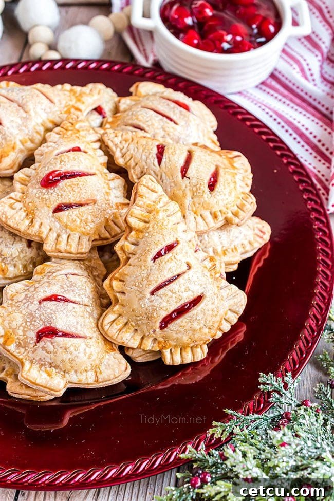 A festive red platter showcasing delicious Holiday Tree Cherry Hand Pies, shaped like Christmas trees.