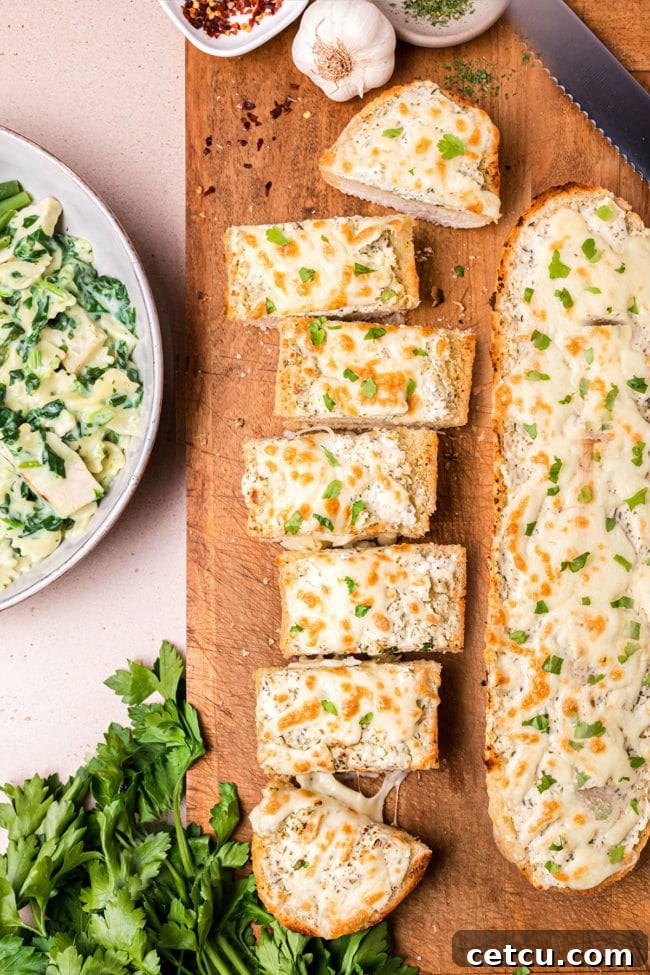 Two loaves of freshly baked cheesy garlic bread on a rustic cutting board, ready to be sliced and served.