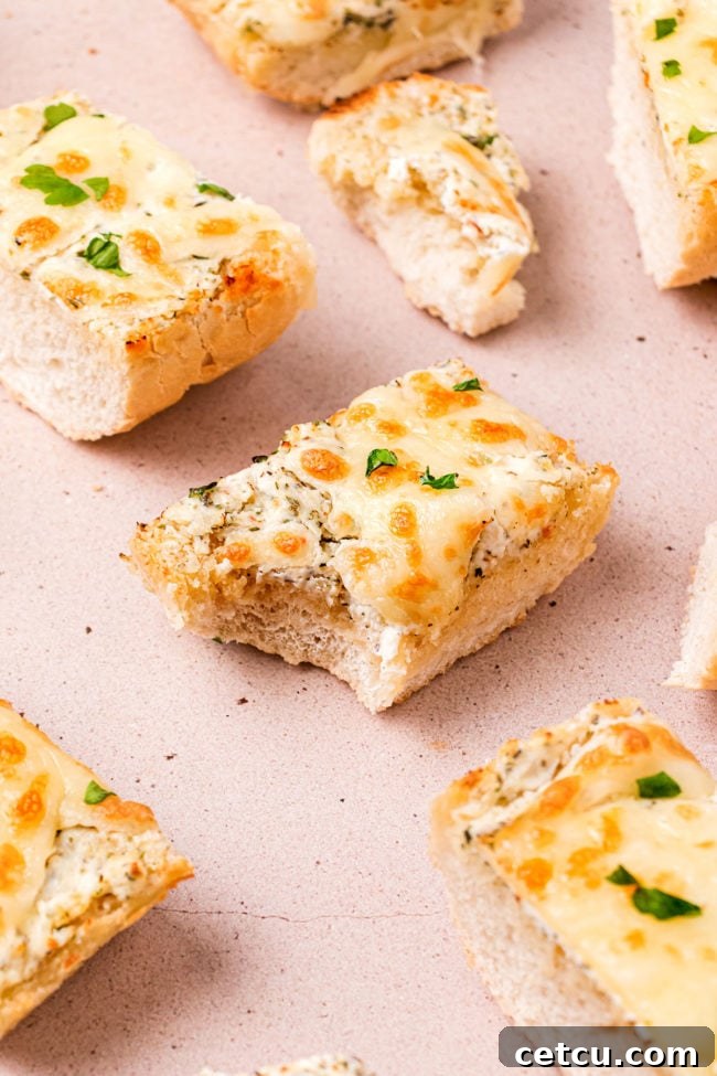 A slice of Cheesy Garlic Bread with a bite taken out, revealing the creamy cheese and soft interior.