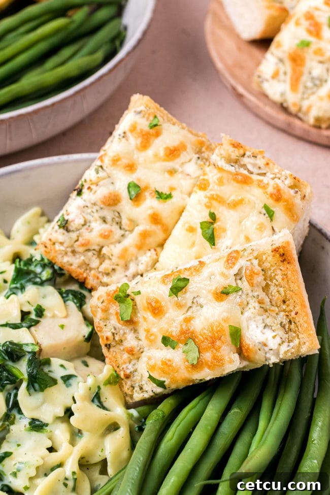 A plate featuring a serving of Cheesy Garlic Bread alongside a portion of pasta and green beans, depicting a complete meal.