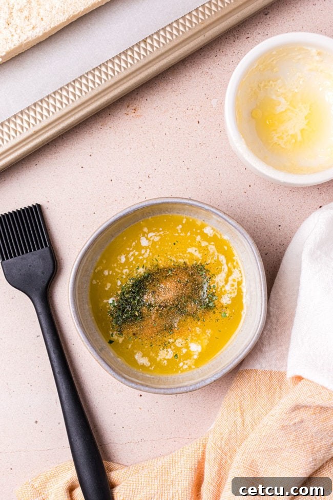 Melted butter combined with garlic powder and dried parsley in a small bowl, forming the seasoned garlic butter mixture.