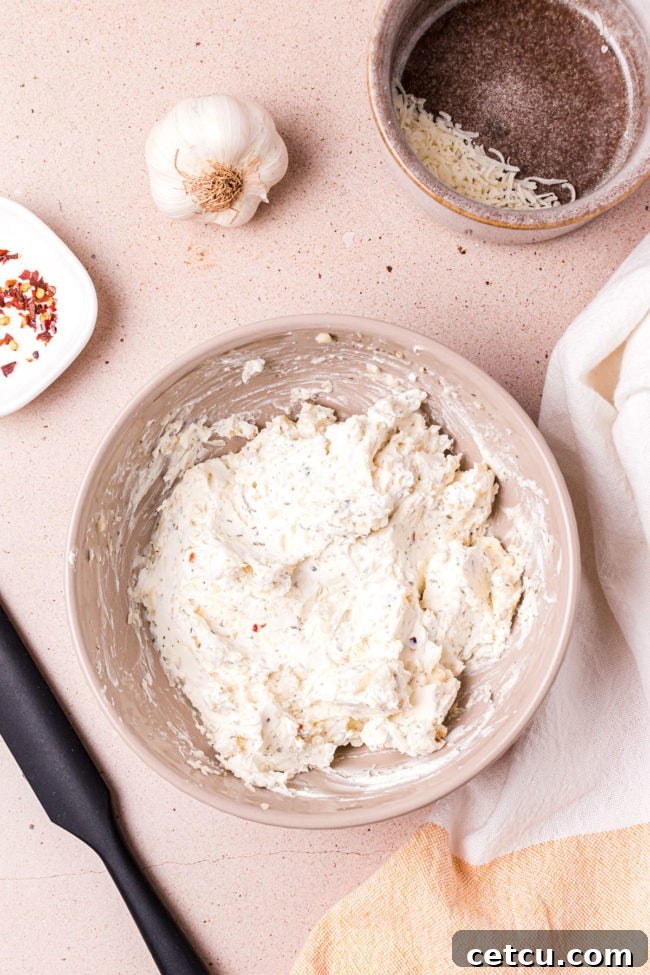 The fully mixed, creamy garlic cheese spread in a bowl, ready to be applied to the bread.
