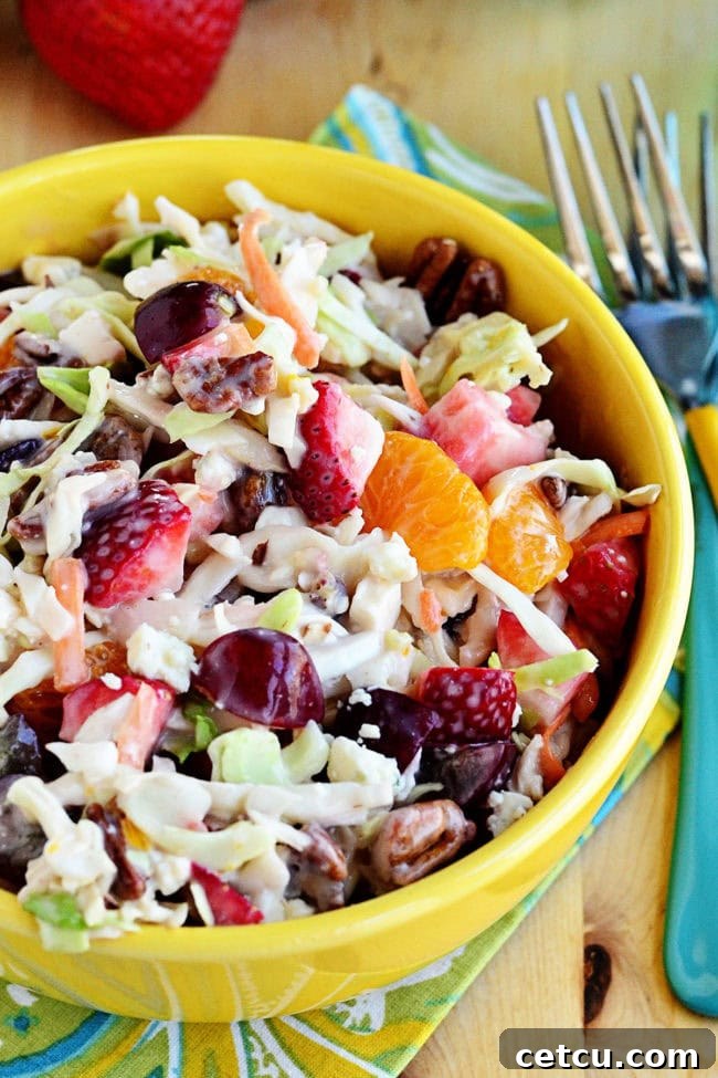 Slaw with mixed fruits and pecans in a large serving bowl, ready to be chilled.