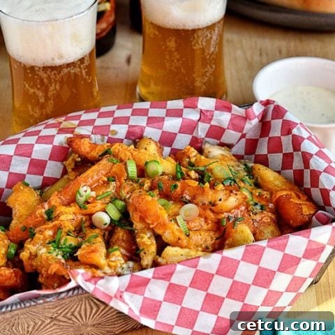 A final presentation of Buffalo Cheese Fries in a serving bowl, garnished with fresh herbs and ready to eat.