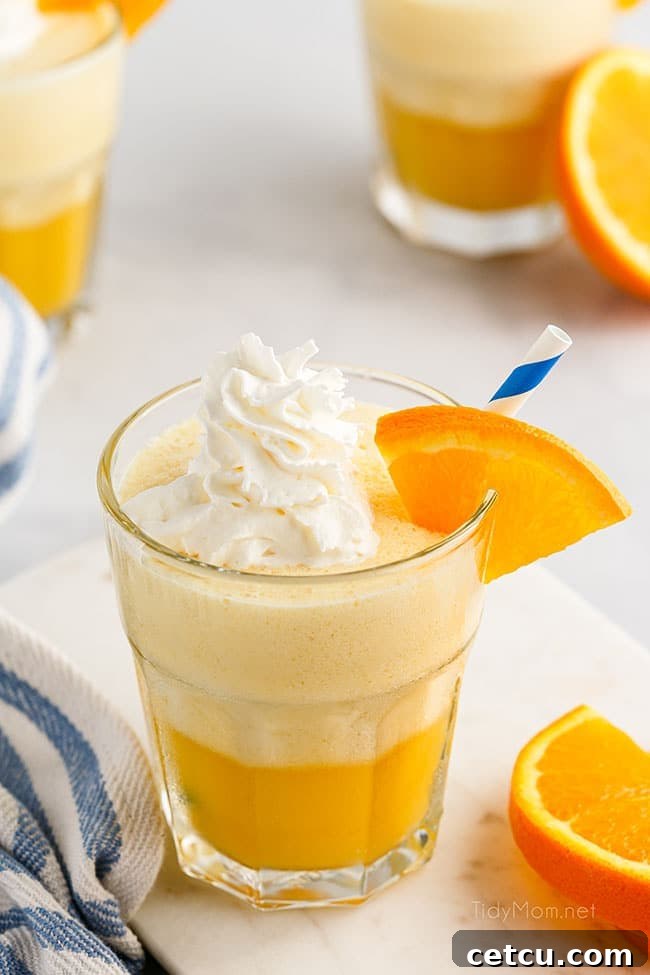 A close-up shot of a glass of Orange Julius, generously topped with creamy whipped cream, emphasizing its signature frothy texture and inviting appearance.