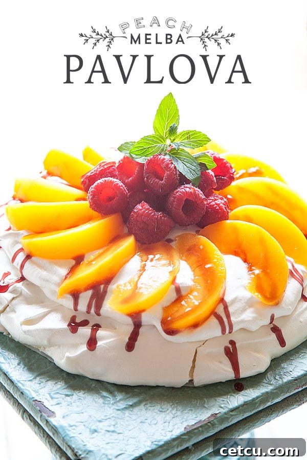 Easy Peach Melba Pavlova, a beautiful summer dessert topped with fresh fruit, on a pristine white tray.