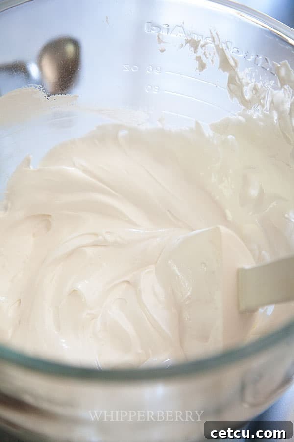 Fluffy white meringue mixture in a clear mixing bowl, ready for baking.