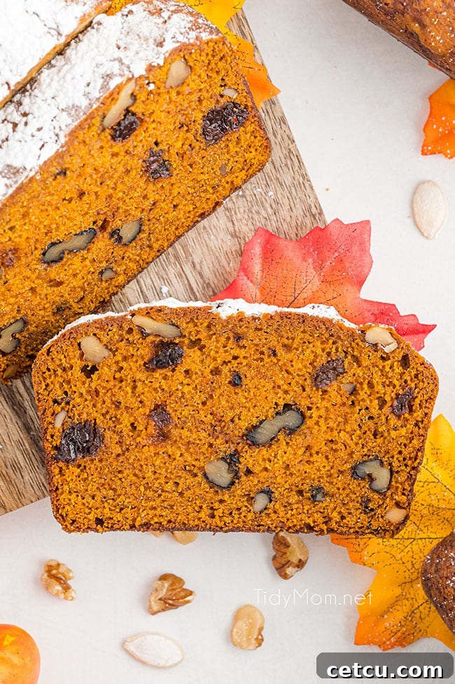 A perfectly baked slice of pumpkin bread, rich in color and texture, stands upright on a cutting board, ready to be enjoyed.