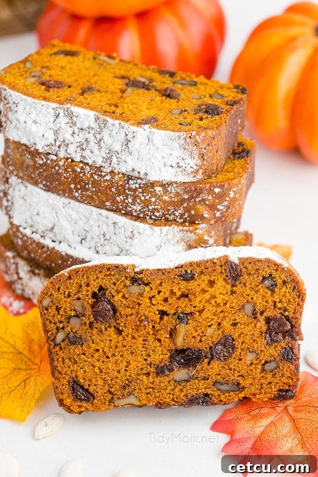 A tempting stack of perfectly sliced pumpkin bread sits invitingly on a wooden board, showcasing its rich texture and warm color.