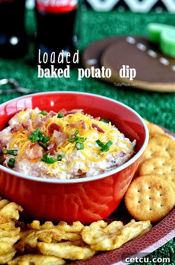 A bowl of creamy Loaded Baked Potato Dip, garnished with chives and bacon, surrounded by Ritz crackers.