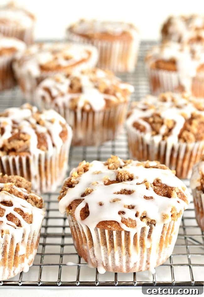 Warm Apple Spice Muffins with Streusel Topping cooling on a wire rack, freshly drizzled with sweet white vanilla icing.