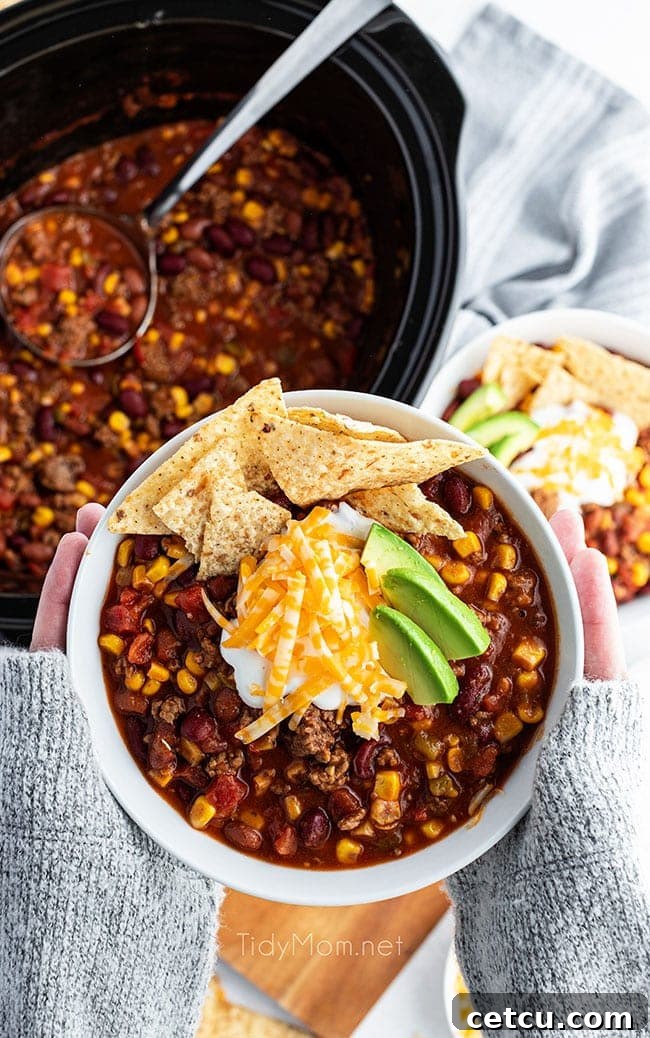 A person's hands gently hold a warm bowl of Slow Cooker Taco Soup, showcasing its comforting appeal.