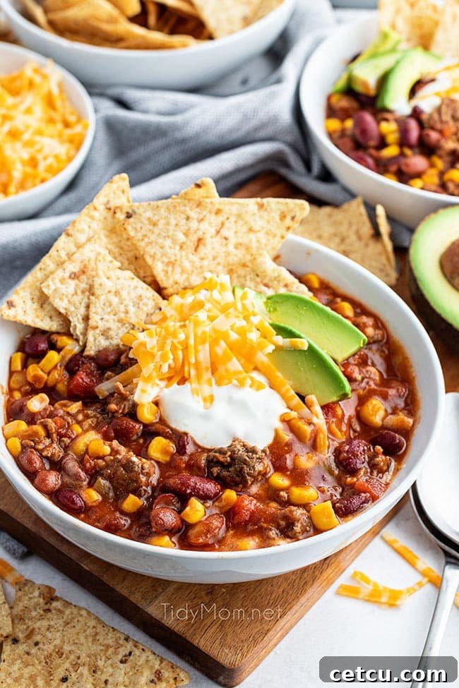 A bowl of slow cooker taco soup artfully garnished with various toppings and surrounded by tortilla chips.