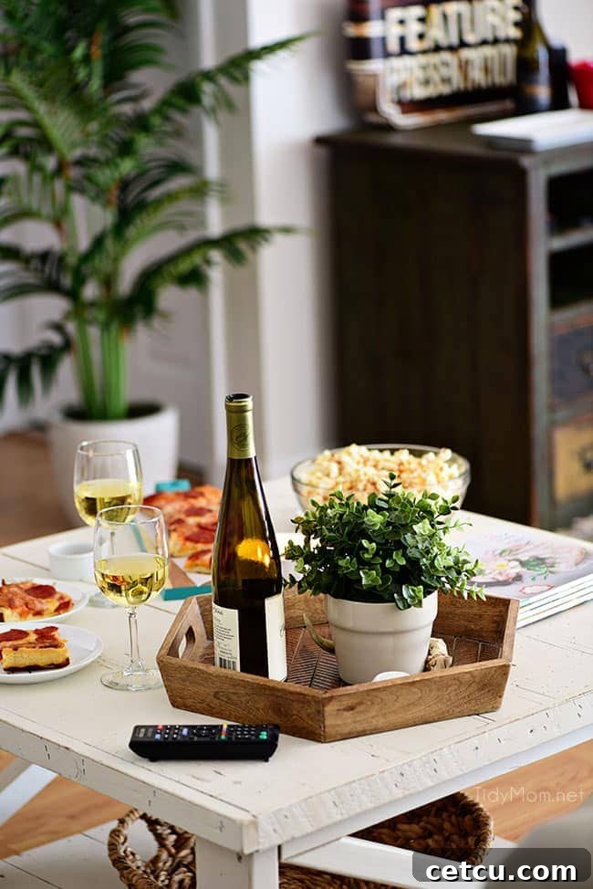 A perfectly curated cozy movie night setup with Sweet Heat Maple-Chili Gourmet Popcorn, slices of DIGIORNO pizza, and refreshing beverages. This photo emphasizes the comfort and ease of creating a special date night at home. Find the gourmet popcorn recipe at TidyMom.net.