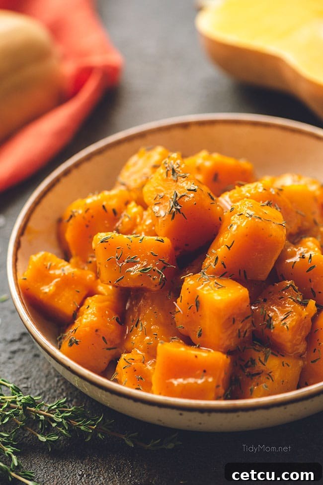 A serving of maple braised butternut squash in a rustic bowl, garnished with fresh thyme, highlighting its tender texture and rich color.