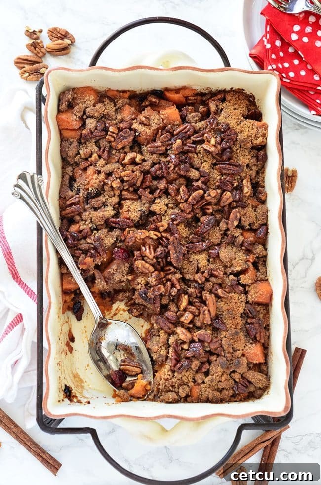 A baking dish filled with Roasted Sweet Potatoes with Cinnamon Pecan Crunch, featuring a golden-brown, crumbly topping.