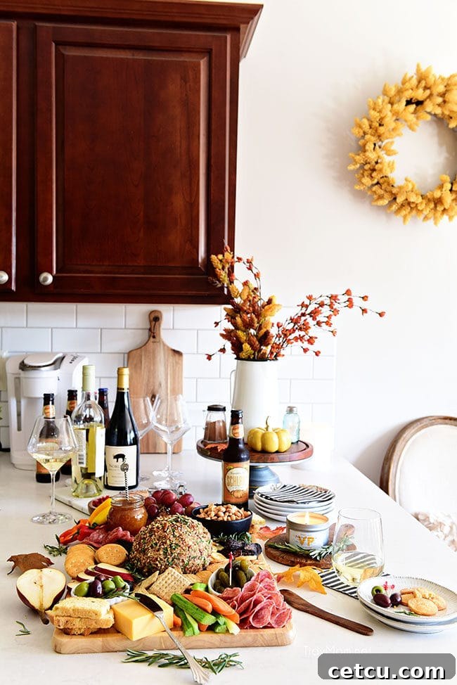 Beautiful Fall Charcuterie Board displayed in a white kitchen, alongside a glass of wine, featuring cheeses, fruits, nuts, and crackers.