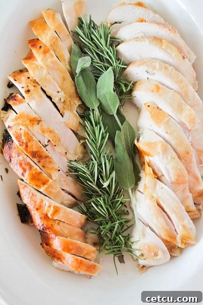 A perfectly roasted Rosemary Sage Turkey breast from The Baker Upstairs, sliced to reveal juicy meat, garnished with fresh herbs.