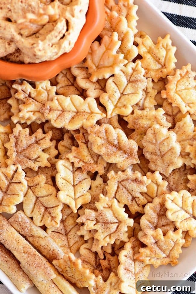 A platter of golden-brown Pie Crust Cookies, dusted with cinnamon sugar, alongside a bowl of pumpkin fluff dip, perfect for a cozy treat.