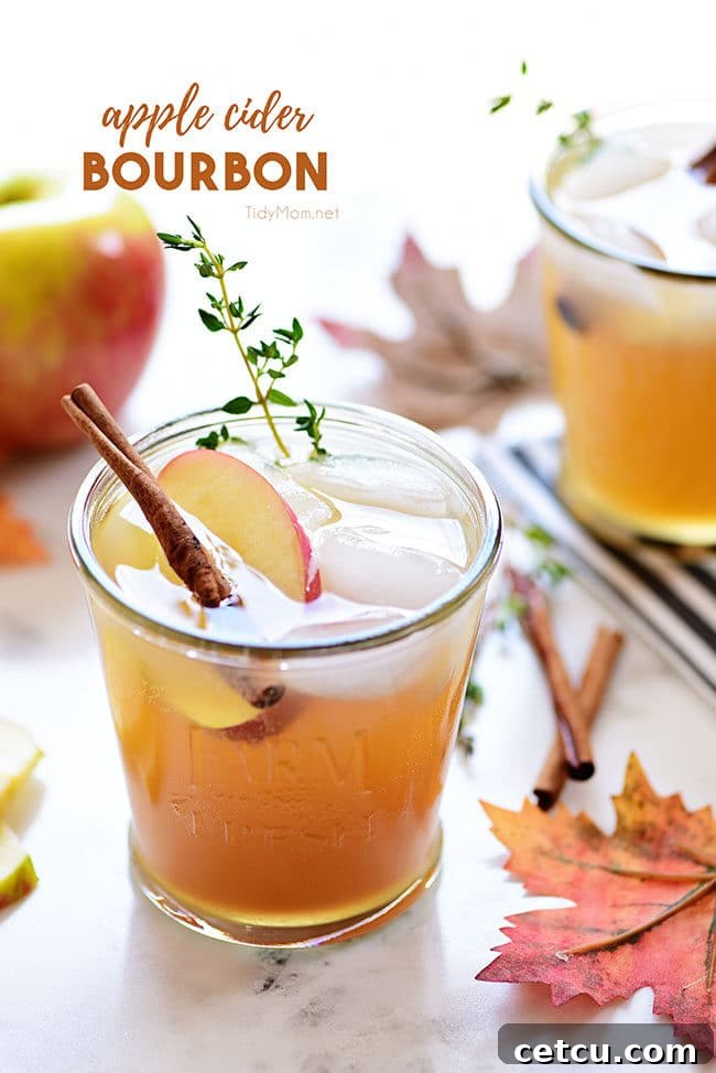 A sophisticated bourbon apple cider cocktail, garnished with a sprig of thyme, ready for sipping at a fall gathering.