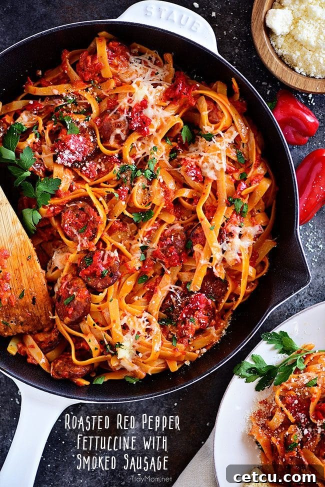 Delicious Roasted Red Pepper Fettuccine with Smoked Sausage in white Staub skillet, garnished with fresh parsley.