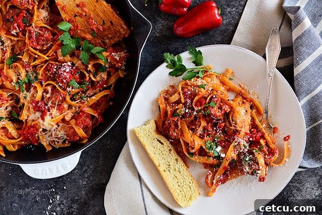 Roasted Red Pepper Fettuccine with Smoked Sausage artfully plated on a white dish, ready to serve.