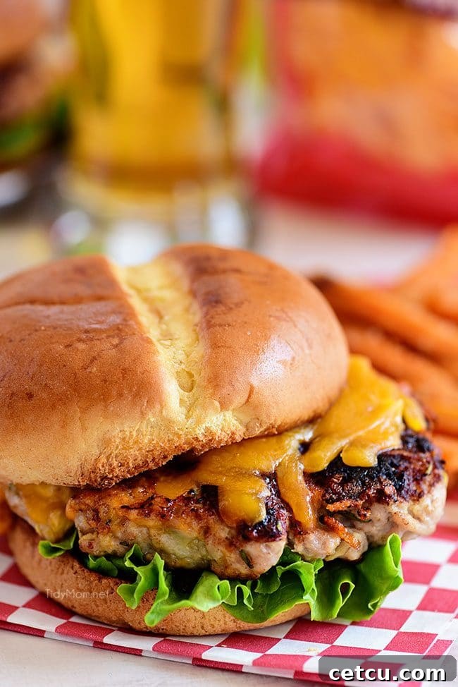 Close-up of a perfectly cooked Apple Cheddar Pork Burger, showing the melted sharp cheddar and inviting texture, ready to be served.