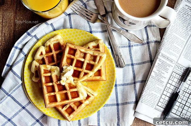 A stack of golden, crispy buttermilk waffles ready for a delicious breakfast, topped with fresh fruit and syrup.